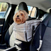 Cane piccolo in trasportino auto beige scozzese fissato al bracciolo centrale per viaggi sicuri